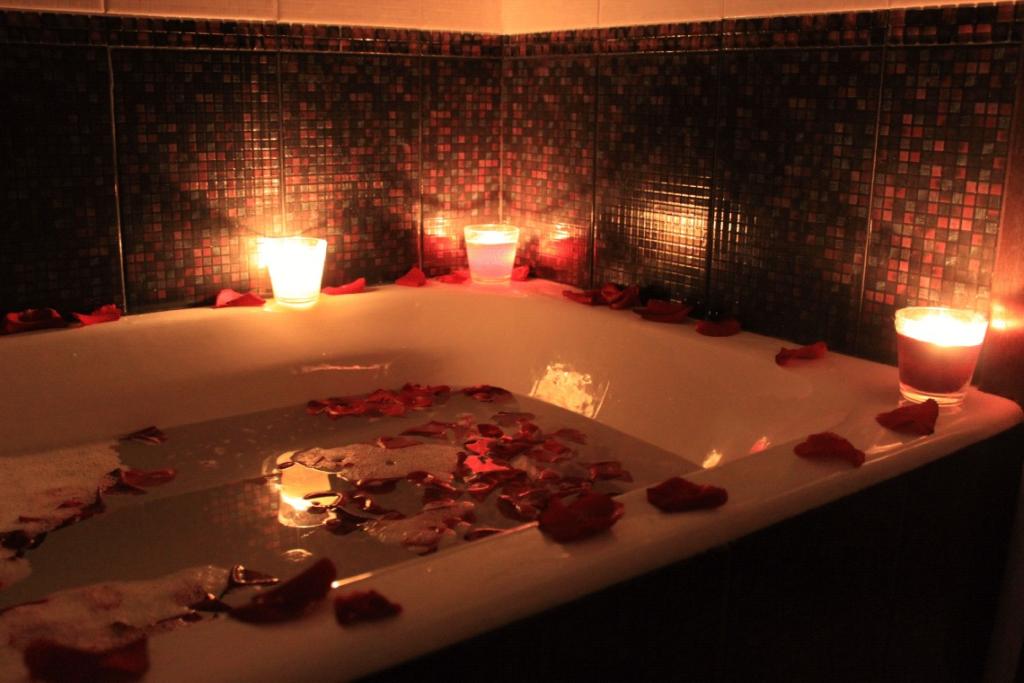 Banheira com água e pétalas de rosa com velas acesas nas bordas